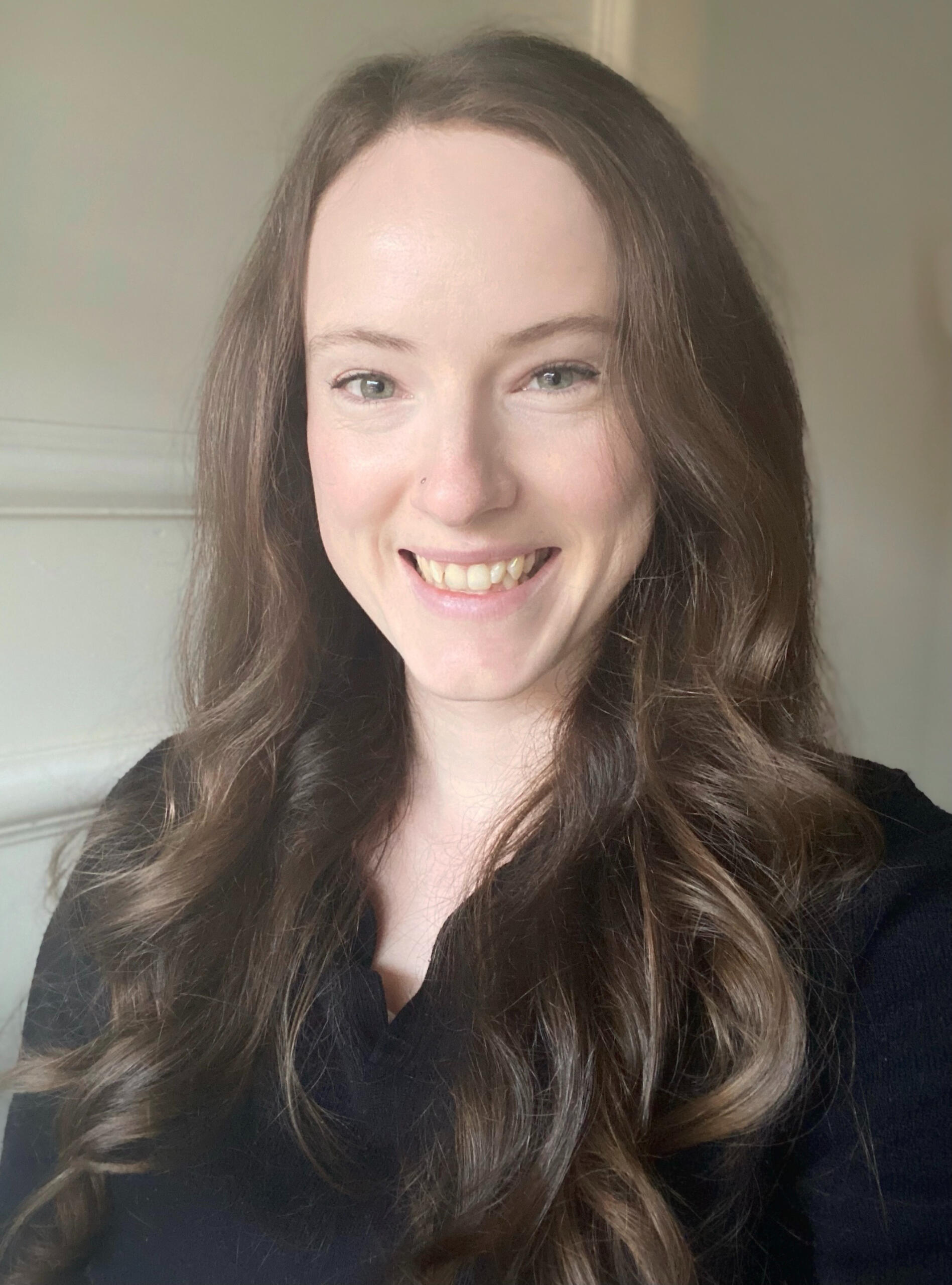 A portrait photograph of Becca, a brown-haired speech pathologist, smiling at the camera.